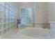 Close-up of bathtub with shutters and a tile-bordered surround with glass blocks at 9091 Alexandria Dr, Weeki Wachee, FL 34613