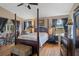 Comfortable main bedroom featuring a four-poster bed, ceiling fan and natural light from the large windows at 11008 Torrey Pines Ct, Hudson, FL 34667
