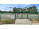 Outdoor tennis court with lighting and seating area under green awning in a fenced-in area at 11008 Torrey Pines Ct, Hudson, FL 34667