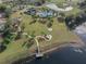 An aerial view shows the community pool, clubhouse, playground, and surrounding natural landscaping near the lake at 13357 Marble Sands Ct, Hudson, FL 34669
