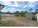 Spacious backyard featuring a tranquil lake view, white fence, and shed at 13357 Marble Sands Ct, Hudson, FL 34669