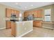 Well-lit kitchen featuring wood cabinets, a center island, granite counters and stainless steel appliances at 1442 Lenton Rose Ct, Trinity, FL 34655
