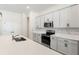 Well-lit kitchen featuring stainless steel appliances, white cabinets, and a quartz countertop island with a sink at 14421 Nonna Sky Drive Dr, Spring Hill, FL 34609