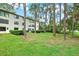 Beautiful view of the backyard featuring lush green grass, large trees and the building exterior at 3038 Eastland Blvd # F103, Clearwater, FL 33761