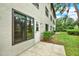 View of the home's exterior featuring a door, large window, and a small patio with landscaping at 3038 Eastland Blvd # F103, Clearwater, FL 33761