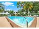 Outdoor community pool with chairs for lounging on the pool deck in a lushly landscaped area at 3038 Eastland Blvd # F103, Clearwater, FL 33761