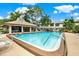 Community pool and covered pavilion area with seating and lush landscaping on a sunny day at 3038 Eastland Blvd # F103, Clearwater, FL 33761