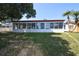 A view of the backyard exterior of this home with multiple windows and a grassy lawn at 3526 Overland Dr, Holiday, FL 34691