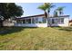 A view of the backyard exterior of this home with multiple windows and a grassy lawn at 3526 Overland Dr, Holiday, FL 34691