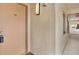 Hallway featuring the front door to unit 104, textured walls, sconce lighting and glimpses of the ocean at 4620 Bay Blvd # 1154, Port Richey, FL 34668