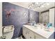 Bathroom with a sink, large mirror and a purple textured wall with flower decorations at 5640 Ferguson Ct # 2208, New Port Richey, FL 34652