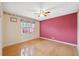 Bedroom with a ceiling fan, hardwood floors, and a neutral color scheme with red accent wall at 6112 Kinlock Ave, Spring Hill, FL 34608