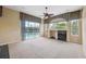 Bright living room with a fireplace, large windows overlooking the pool, and a ceiling fan at 6112 Kinlock Ave, Spring Hill, FL 34608