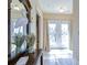 A sunlit hallway featuring tiled flooring, a decorative heron, and glass paneled doors at 6801 Nowiki Ave, Hudson, FL 34667