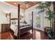 This bedroom has a four-poster bed, hardwood floors, and double doors leading to a balcony at 7256 Westwind St, Weeki Wachee, FL 34607