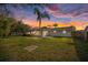 Expansive backyard featuring a screen-enclosed porch, mature trees, and a privacy fence at sunset at 7431 Abington Ave, New Port Richey, FL 34655