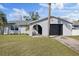 Charming home featuring a stucco exterior, front lawn, palm trees, and an attached garage with a black door at 7431 Abington Ave, New Port Richey, FL 34655