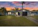 Charming home featuring a stucco exterior, front lawn, palm trees, and an attached garage with a black door at 7431 Abington Ave, New Port Richey, FL 34655