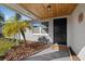 Inviting front porch with a decorative wood ceiling, a black front door, and decorative landscaping at 7431 Abington Ave, New Port Richey, FL 34655