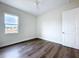 Well-lit bedroom features a window, wood-look flooring, and neutral decor, creating a calming space at 9065 Mississippi Run, Weeki Wachee, FL 34613