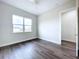 Light and airy bedroom with a large window, wood-look flooring, and open doorway to hall at 9065 Mississippi Run, Weeki Wachee, FL 34613