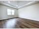Spacious bedroom with ceiling fan, tray ceiling, large window, and wood-look flooring at 9065 Mississippi Run, Weeki Wachee, FL 34613