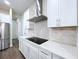 Modern kitchen with cooktop, stainless steel hood, white cabinets and countertops at 9065 Mississippi Run, Weeki Wachee, FL 34613