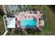 Aerial view of a large rectangular pool with lounge chairs and palm trees surrounded by a brick patio at 9065 Mississippi Run, Weeki Wachee, FL 34613