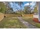 Backyard featuring new wooden fence, mature trees, and a stone firepit area at 9250 Peony St, New Port Richey, FL 34654