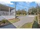 Gravel driveway leads to a charming home with a welcoming porch, surrounded by mature trees at 9250 Peony St, New Port Richey, FL 34654