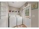 Bright laundry room with washer, dryer, shelving, and exterior access door at 9250 Peony St, New Port Richey, FL 34654