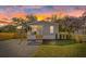 Charming home with sunset backdrop, featuring a cozy front porch, and a gravel driveway at 9250 Peony St, New Port Richey, FL 34654