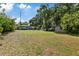 Large backyard with mature trees, a shed, and the rear of a charming light-blue home at 1101 N Betty Ln, Clearwater, FL 33755