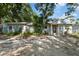 Charming single-story home featuring a red front door, light blue paint, stone trim, and lush landscaping at 1101 N Betty Ln, Clearwater, FL 33755