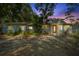 Charming single-story home featuring a red front door, light blue paint, stone trim, and lush landscaping at dusk at 1101 N Betty Ln, Clearwater, FL 33755