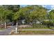 A serene front exterior of the house with a black iron fence, lush greenery, and a large shade tree at 1101 N Betty Ln, Clearwater, FL 33755