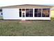 A view of the backyard showing the enclosed patio and the red mulch along the base of the home at 11204 Clear Oak Cir, New Port Richey, FL 34654