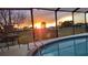 Sunset view from screened-in pool with ample patio space, ideal for entertaining and enjoying the outdoors at 13026 Lawrence St, Spring Hill, FL 34609