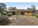 View of the backyard, with a flat area covered in dry grass, and part of the rear exterior at 1358 Newhope Rd, Spring Hill, FL 34606