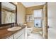 Cozy bathroom with a decorative mirror, white cabinetry, and a window providing natural light and garden views at 1358 Newhope Rd, Spring Hill, FL 34606