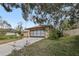 View of the house exterior from the street on a sunny day, framed by lush trees and greenery, highlighting the neighborhood at 1358 Newhope Rd, Spring Hill, FL 34606