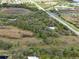 A high-angle aerial view of a sprawling property, showcasing trees, open land, and a house in the distance at 16411 County Road 675, Parrish, FL 34219