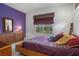 Charming bedroom featuring a purple accent wall, platform bed, and a window with a view at 16411 County Road 675, Parrish, FL 34219