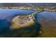 Wide aerial shot of beach with an island full of palm trees, cars, and tranquil waters at 1723 Gulf Rd # 104, Tarpon Springs, FL 34689