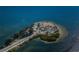 Overhead shot of a charming island connected by a road, dotted with trees, parking, and sandy beach at 1723 Gulf Rd # 104, Tarpon Springs, FL 34689