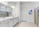 Bright bathroom with a double sink vanity, quartz countertop, large mirror, and glass-enclosed shower at 18629 Coastal Shore Ter, Land O Lakes, FL 34638