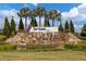 Del Webb Bexley community entrance featuring a water feature, lush landscaping, palm trees and blue skies at 18629 Coastal Shore Ter, Land O Lakes, FL 34638