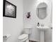 Cozy powder room with a pedestal sink, oval mirror, and decorative artwork at 18629 Coastal Shore Ter, Land O Lakes, FL 34638