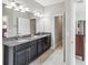Bathroom with double sink, granite countertops, tiled floors, and ample lighting at 19504 Lily Pond Ct, Brooksville, FL 34601