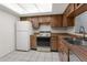 Bright kitchen featuring wood cabinets, white appliances, and tile flooring at 2440 Winding Creek Blvd # 305, Clearwater, FL 33761